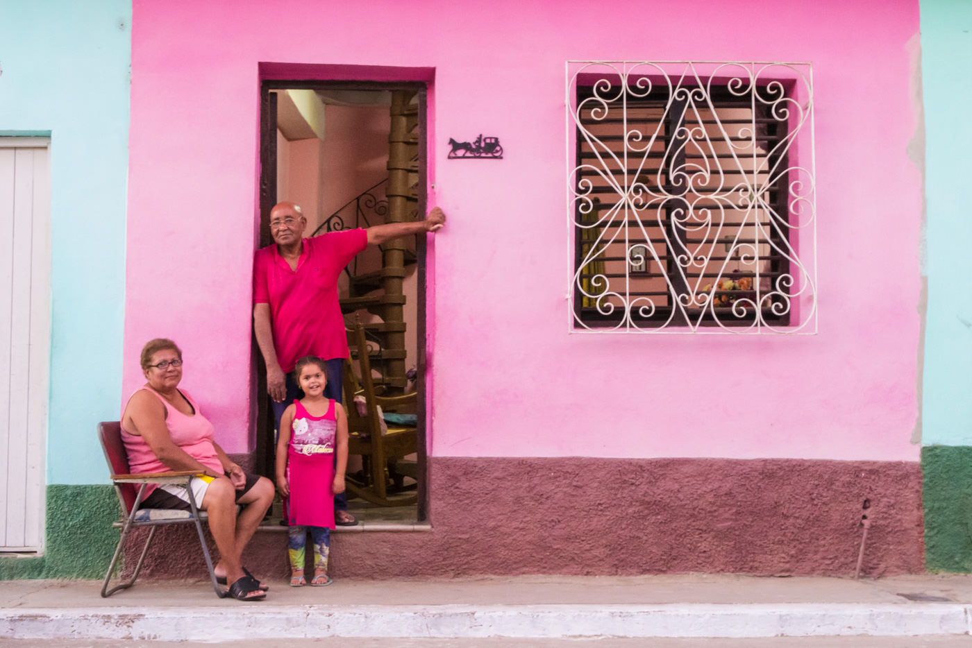 Kubanische Familie ist passend zur Farbe des Hauses gekleidet