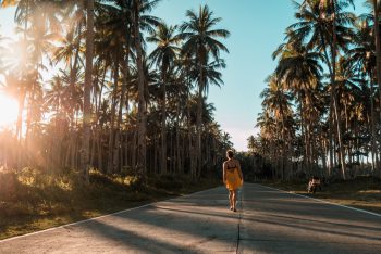 Julia auf der Straße zwischen Palmen auf Siargao, Philippinen