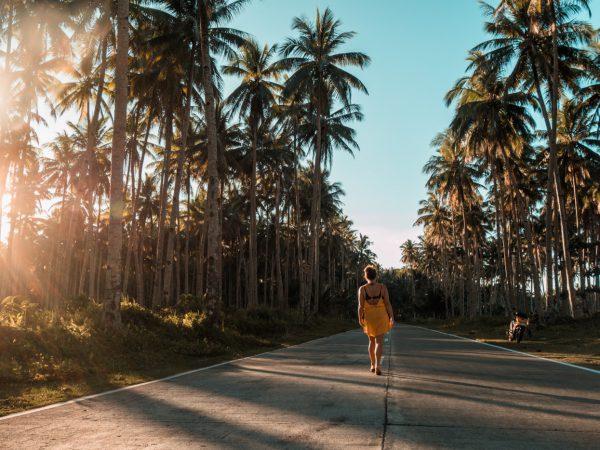 Julia auf der Straße zwischen Palmen auf Siargao, Philippinen