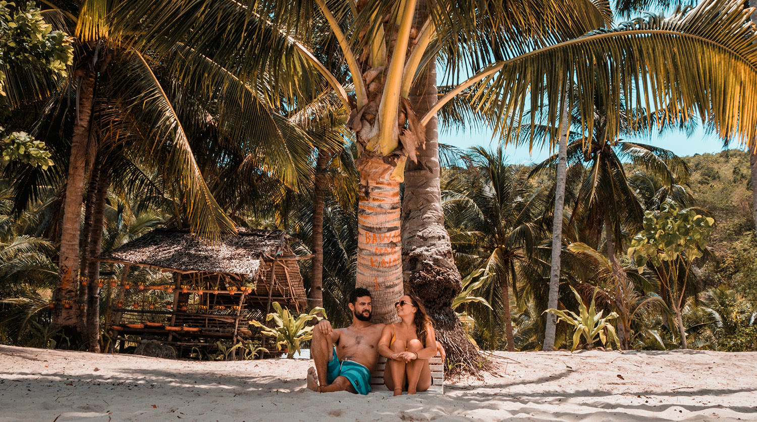 Wir sitzen unter einer Palme am Strand auf den Philippinen